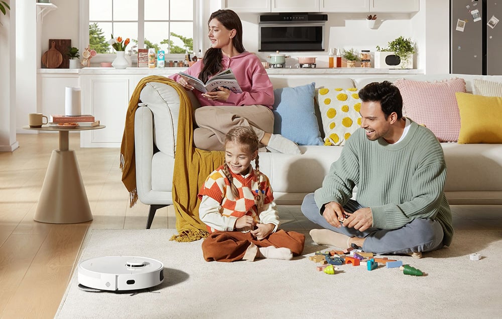 szczęśliwa rodzina spędza wspólnie miło czas, na dywanie robot sprzątający