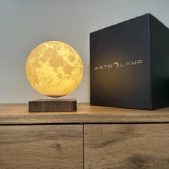 Astrolamp 3D nyomtatott holdlámpa és elegáns csomagolás fa asztalon.
